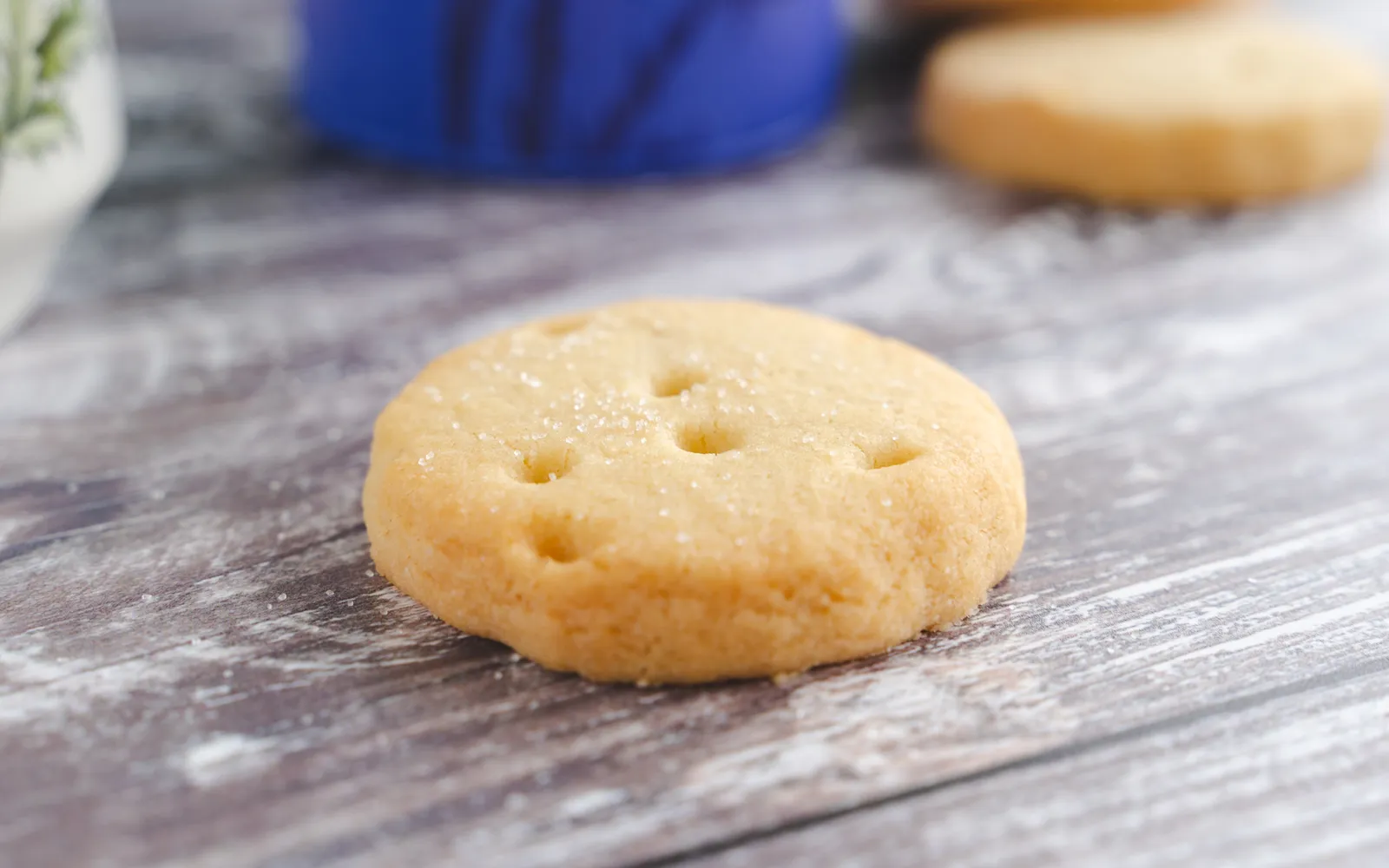 Shortbread สกอตแลนด์ทรงสี่เหลี่ยมสีทองอ่อนวางบนจานสีขาว เนื้อขนมร่วนละเอียดโรยน้ำตาลทรายเล็กน้อยบนผิว
