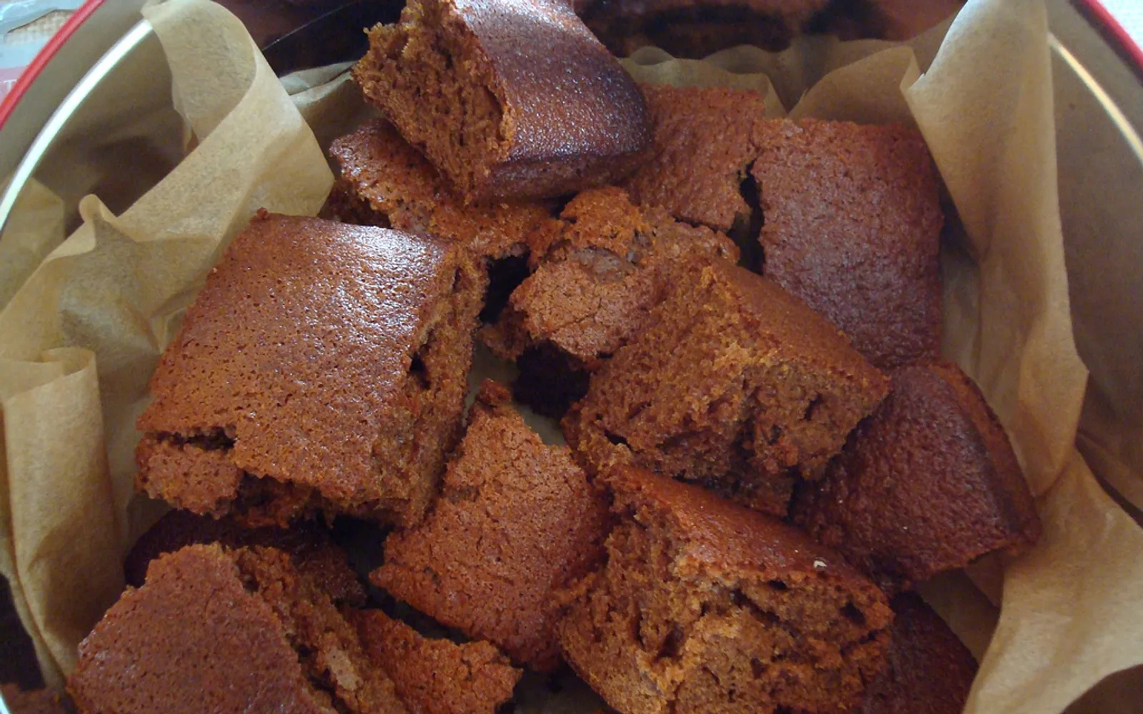 Parkin เค้กสีน้ำตาลเข้มตัดเป็นสี่เหลี่ยมชิ้นหนาวางบนถาดไม้ เนื้อเหนียวนุ่มกรอบขอบ กลิ่นขิงและกากน้ำตาลโชยฟุ้ง
