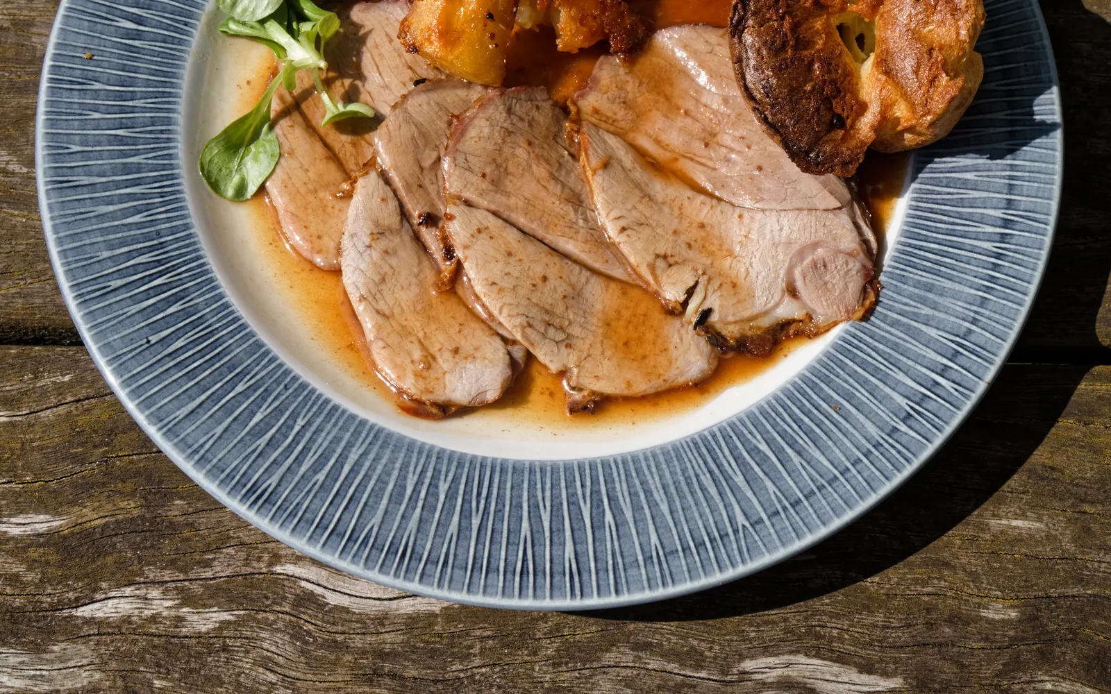 จาน Sunday Roast เต็มจานใหญ่ เนื้อวัวอบสีน้ำตาลทอง มันฝรั่งอบกรอบ ผักลวก Yorkshire Pudding และน้ำเกรวี่สีน้ำตาลข้น