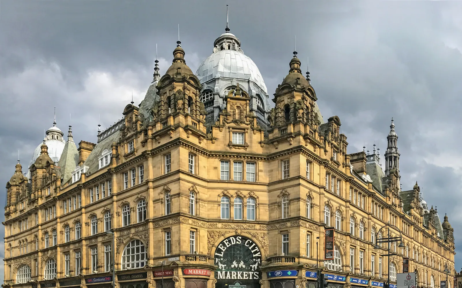 โถงตลาด Leeds Kirkgate Market หลังคาเหล็กและกระจกสไตล์วิกตอเรียนส่องแสงลงมาบนแผงขายอาหารและของสดหลากสีสัน
