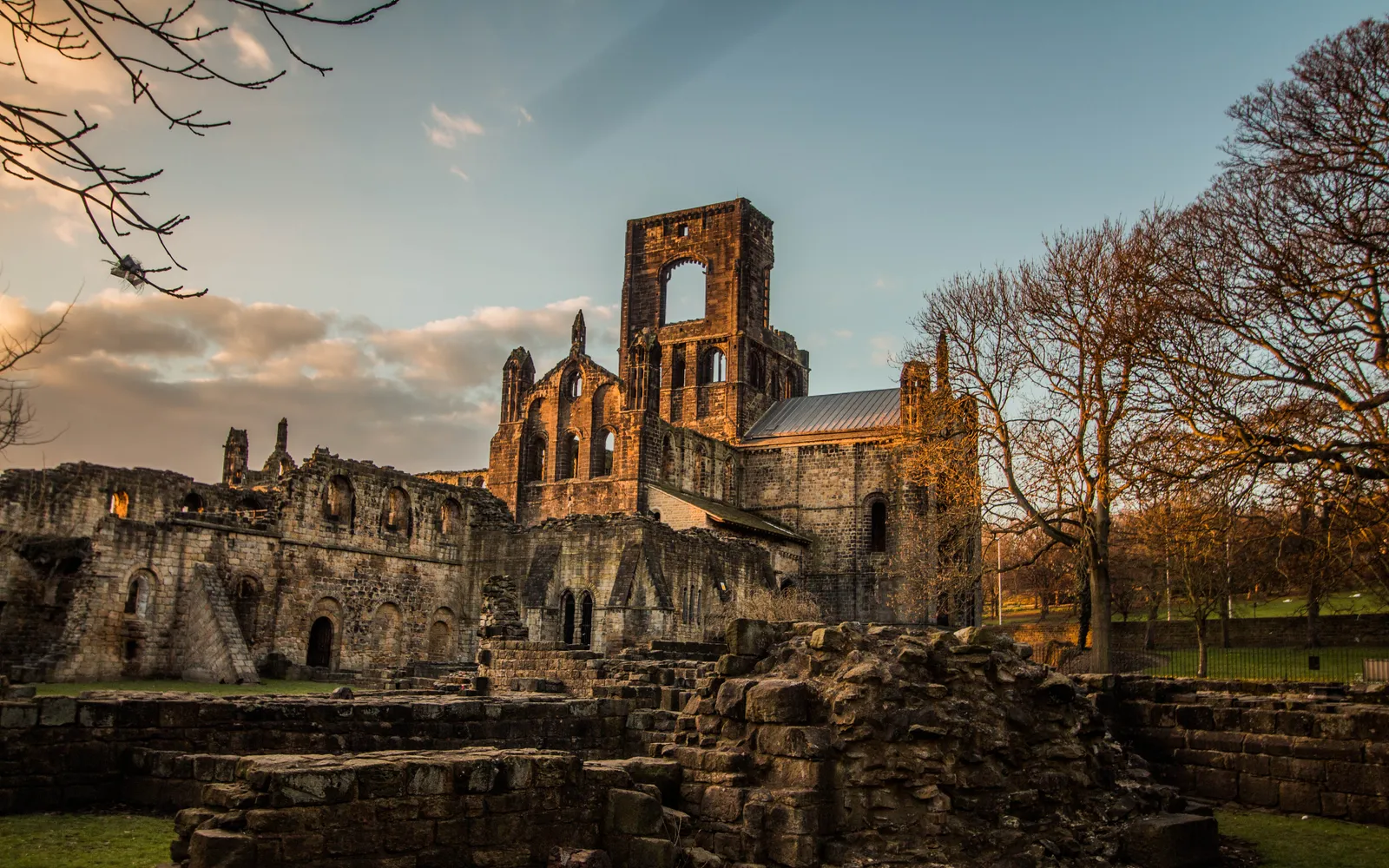 ซากวัด Kirkstall Abbey หินทรายสีน้ำตาลทองตั้งตระหง่านในสวนสีเขียว ซุ้มโค้งโรมาเนสก์ยังสมบูรณ์แม้ผ่านมา 800 กว่าปี