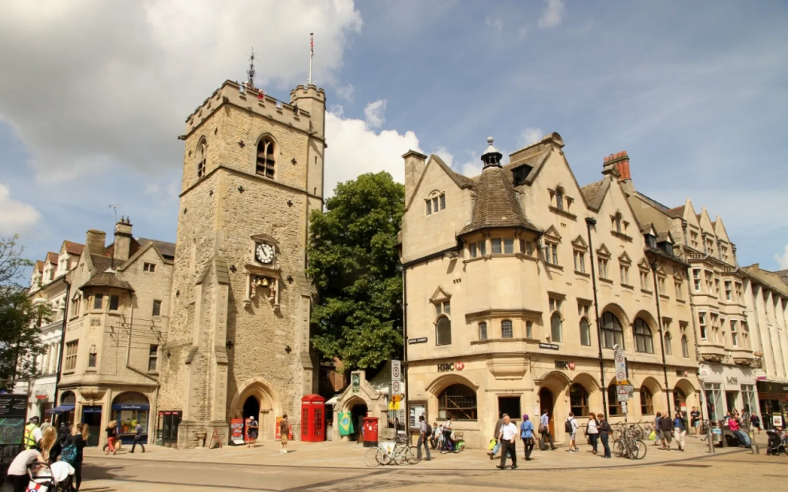หอนาฬิกา Carfax Tower หินสีน้ำผึ้งโบราณตั้งอยู่กลางทางแยกใจกลางอ็อกซ์ฟอร์ด นักท่องเที่ยวเดินรายล้อมบนทางเท้าหินเก่า