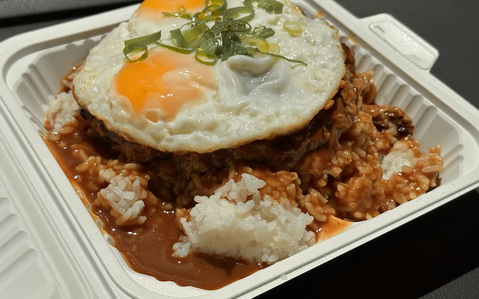 โลโคโมโคจานใหญ่ ข้าวขาวฮาวายรองพื้น วางแฮมเบอร์เกอร์เนื้อ ไข่ดาวสองฟองบนสุด ราดน้ำเกรวีสีน้ำตาลเข้มข้น