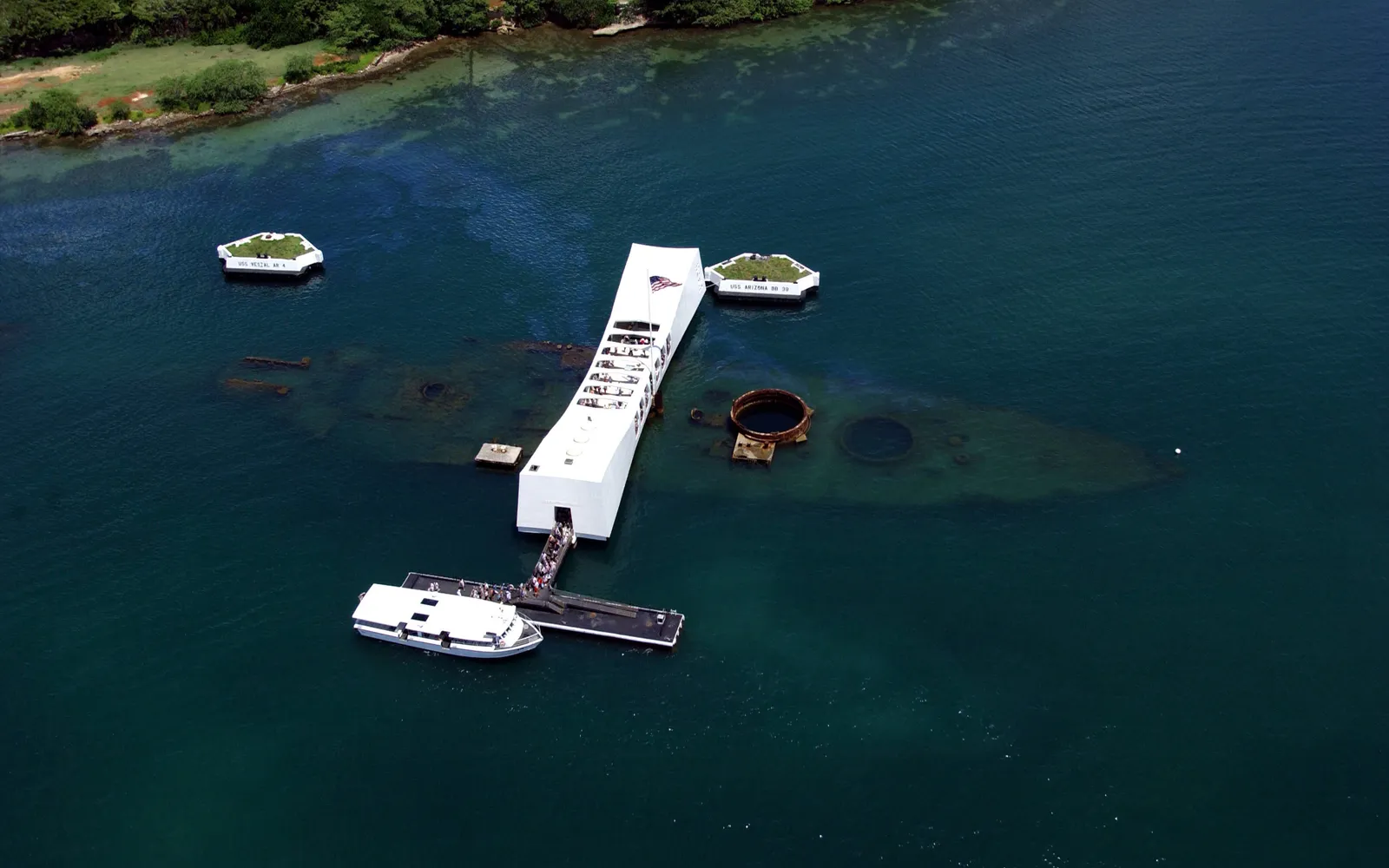 อนุสรณ์สถาน USS Arizona สีขาวลอยเหนือซากเรือรบที่จมในเพิร์ลฮาร์เบอร์ น้ำทะเลสีฟ้าใสมองเห็นโครงเรือใต้น้ำ