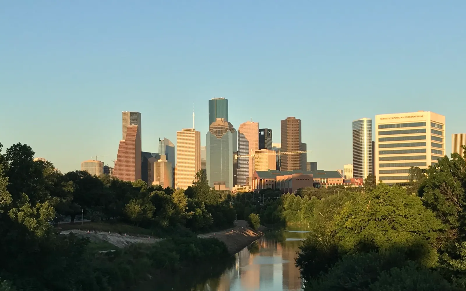 ทางเดินริมน้ำและสะพานในสวน Buffalo Bayou Park ฮิวสตัน พร้อม skyline ในระยะไกล