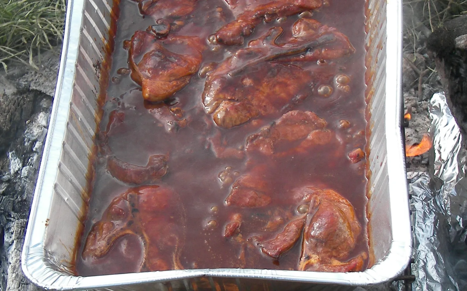 ขวดซอส BBQ สไตล์แคนซัสซิตีสีแดงเข้มวางคู่กับเนื้อรมควัน