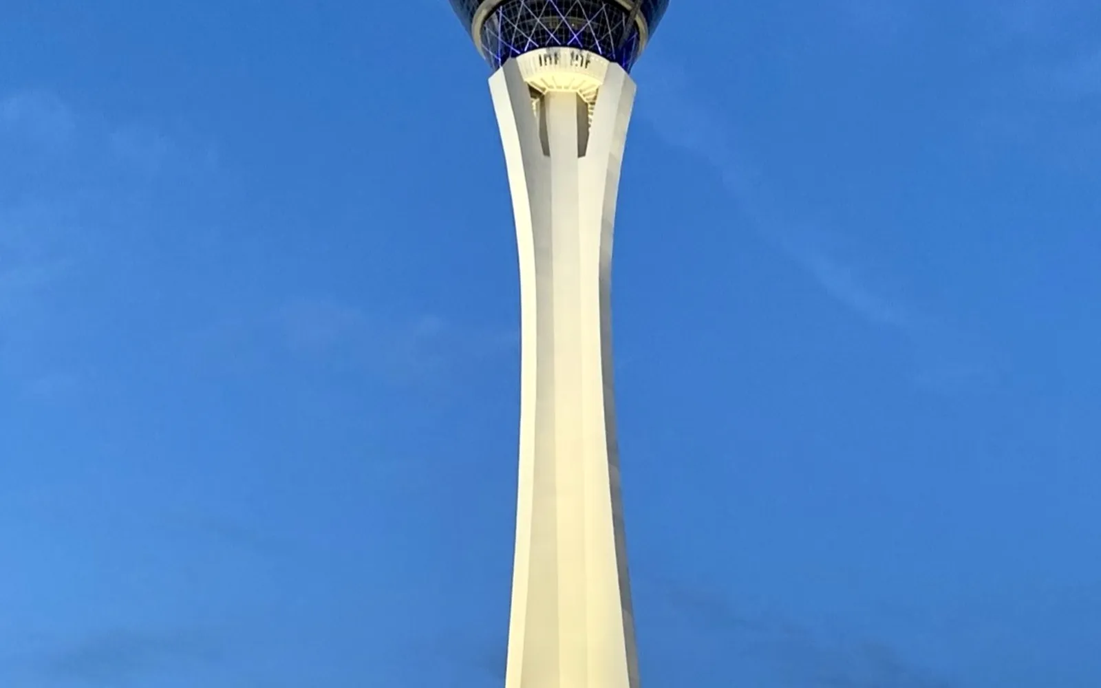The STRAT Tower หอสูงสีขาวสูง 350 เมตรโดดเด่นเหนือ The Strip ยามกลางคืน แสงไฟตัวเมืองลาสเวกัสทอดยาวไปถึงขอบทะเลทรายสุดสายตา
