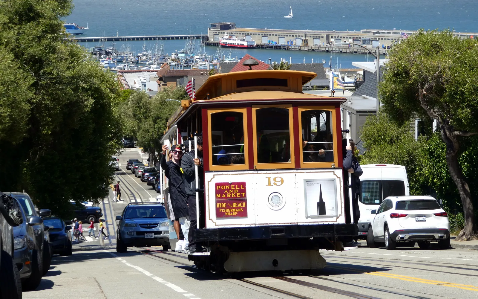 รถราง cable car ไม้คลาสสิกไต่เนินเขาชันในซานฟรานซิสโกพร้อมผู้โดยสารยืนเกาะ