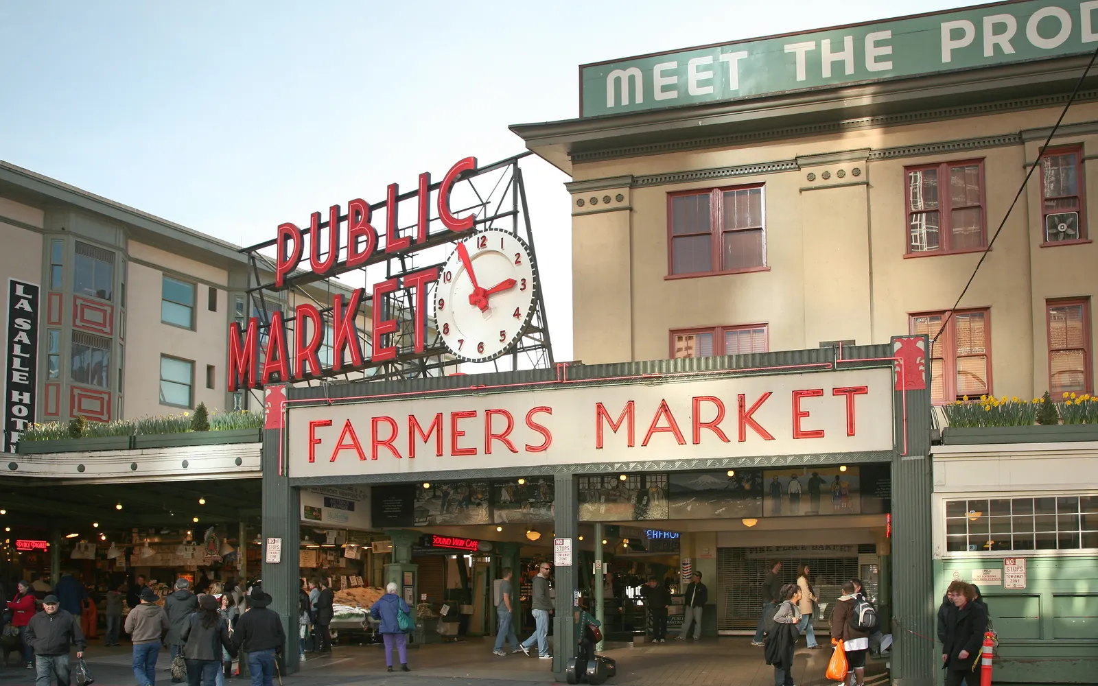 ป้ายไฟสีแดงของ Pike Place Market และแผงขายสินค้าสดที่คึกคัก