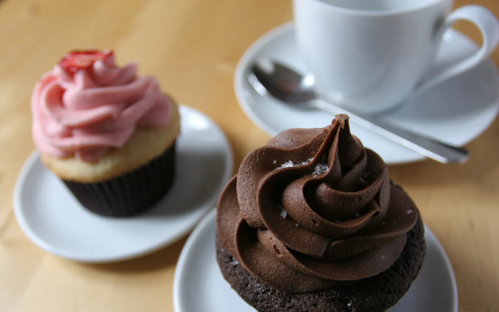 คัพเค้กแต่งหน้าสวยงามจาก Georgetown Cupcake ไอซิ่งโรลสูงสีชมพูพาสเทลบนเค้กช็อกโกแลตเนื้อนุ่ม วางเรียงในกล่องของขวัญสีชมพู