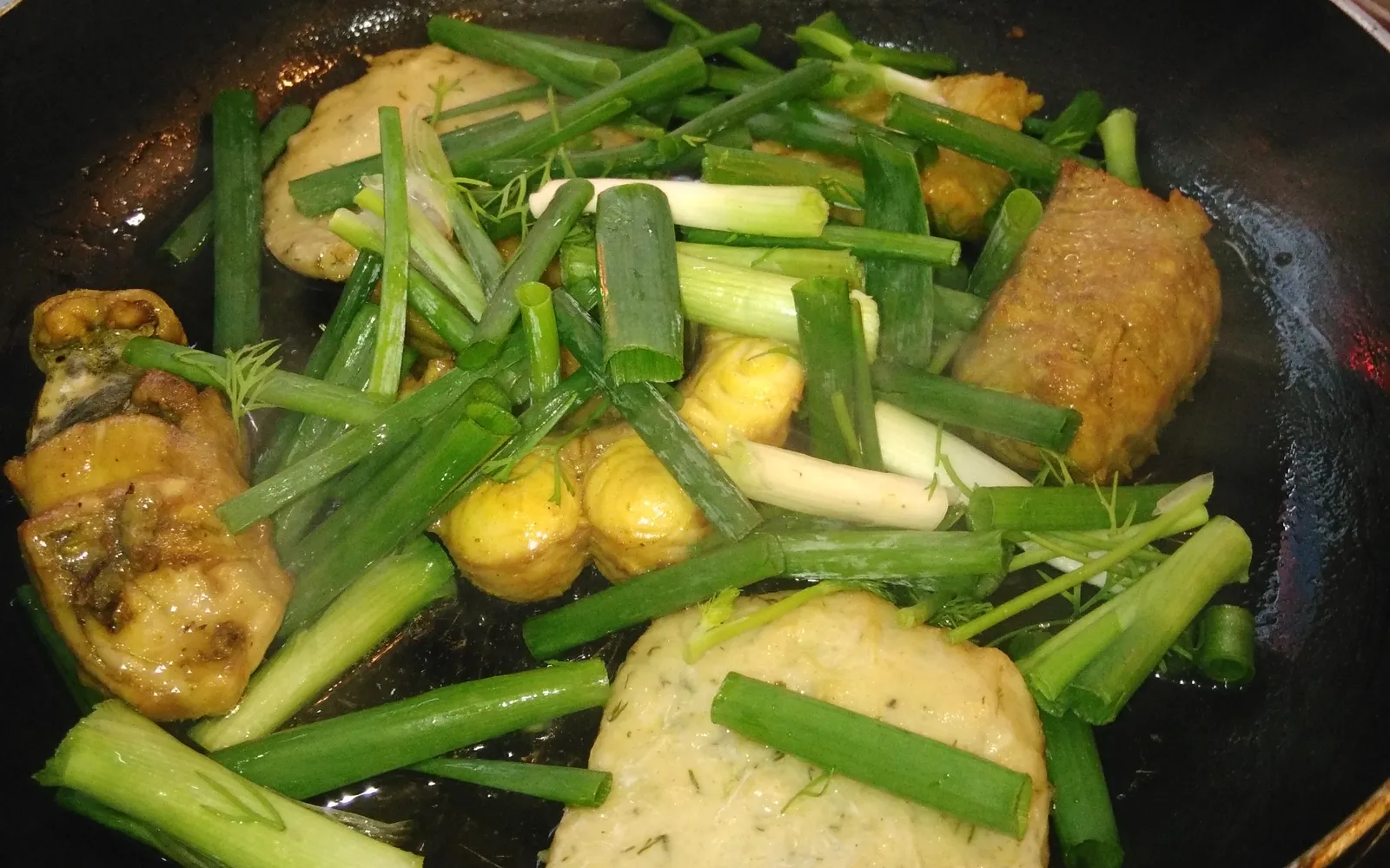 ปลาทอดขมิ้นใส่ผักชีลาวเสิร์ฟบนกระทะเล็กบนโต๊ะกินข้าวสไตล์ฮานอย