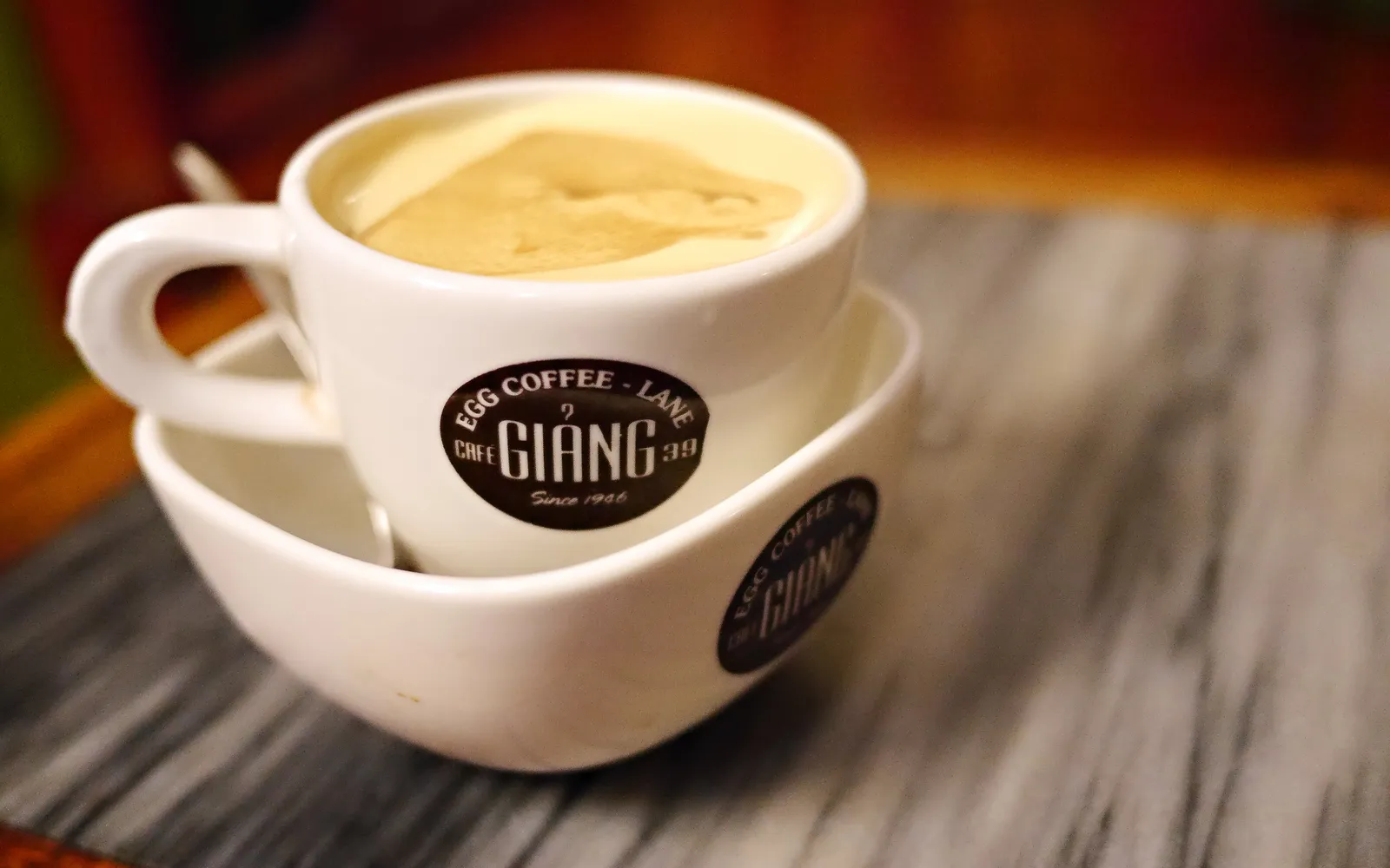 แก้วกาแฟไข่ฮานอยมีครีมไข่สีเหลืองนวลลอยบนกาแฟดำ