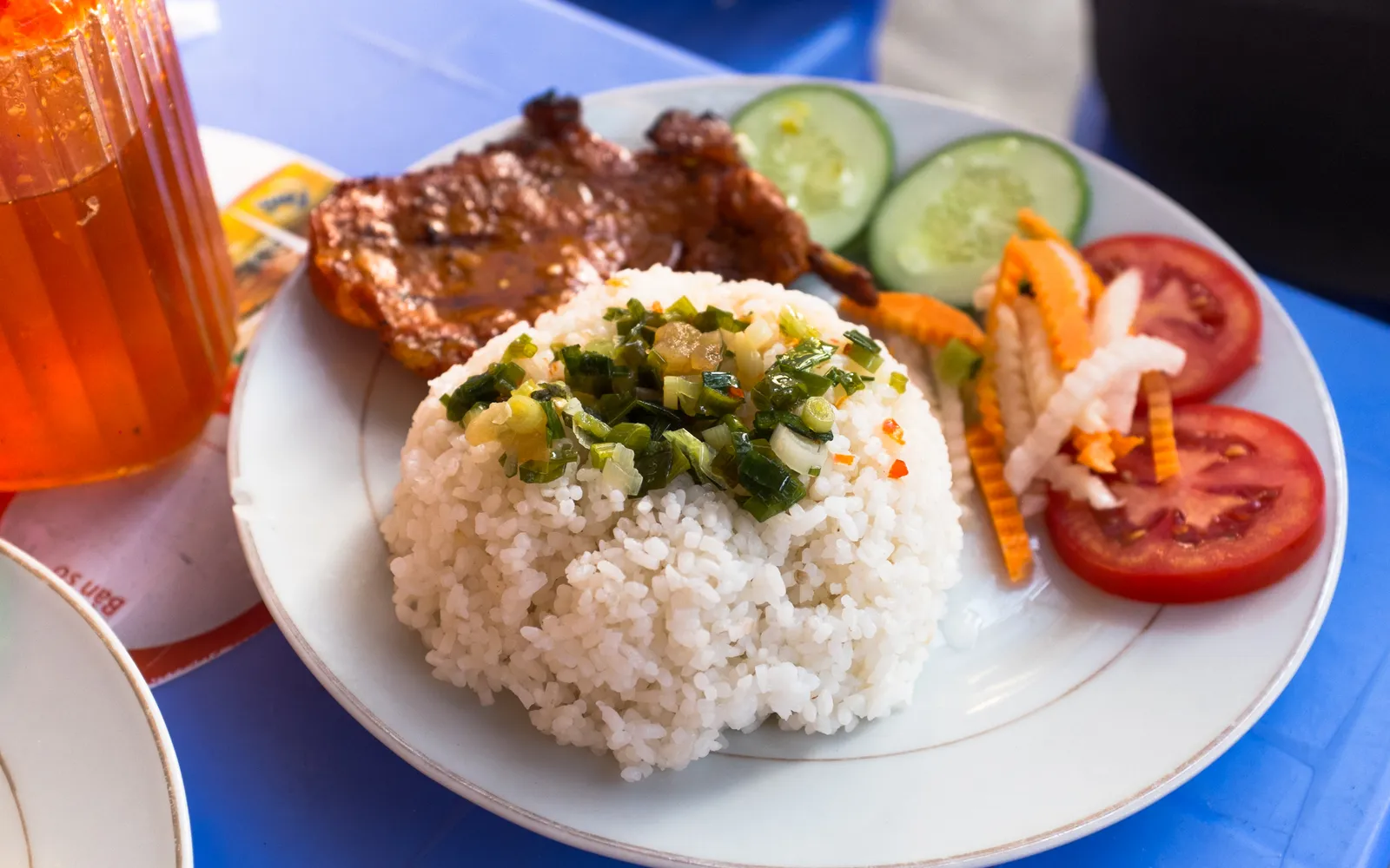 จานข้าวหักก้าวตัมพร้อมหมูซี่โครงย่างสีน้ำตาลทอง ไข่ดาว ผักดอง และน้ำจิ้มปลาหวานเปรี้ยว