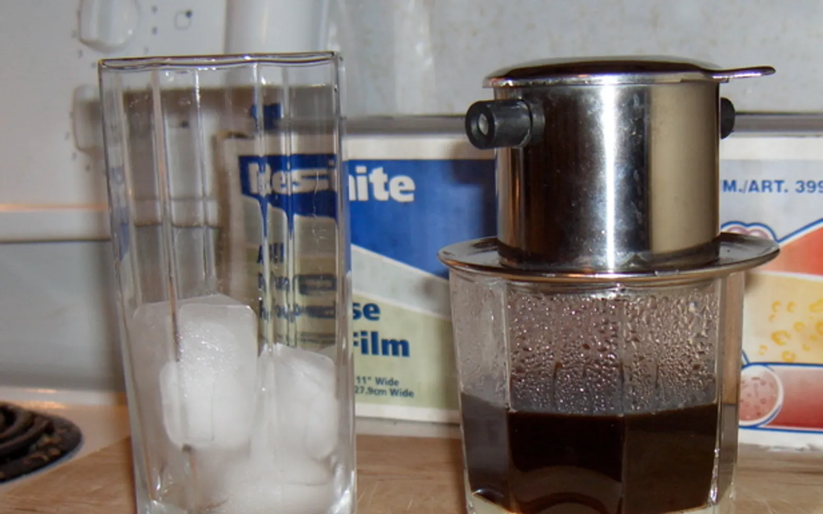 กาแฟเวียดนามสไตล์ Ca Phe Sua Da แก้วสูงน้ำแข็งเต็ม นมข้นหวานสีน้ำตาลไหลลงจากกาแฟดำเข้ม